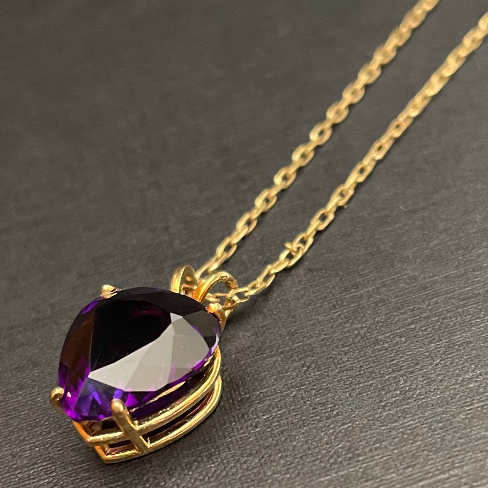 Large plum deep purple amethyst pendant in the shape of a heart on a gold chain.