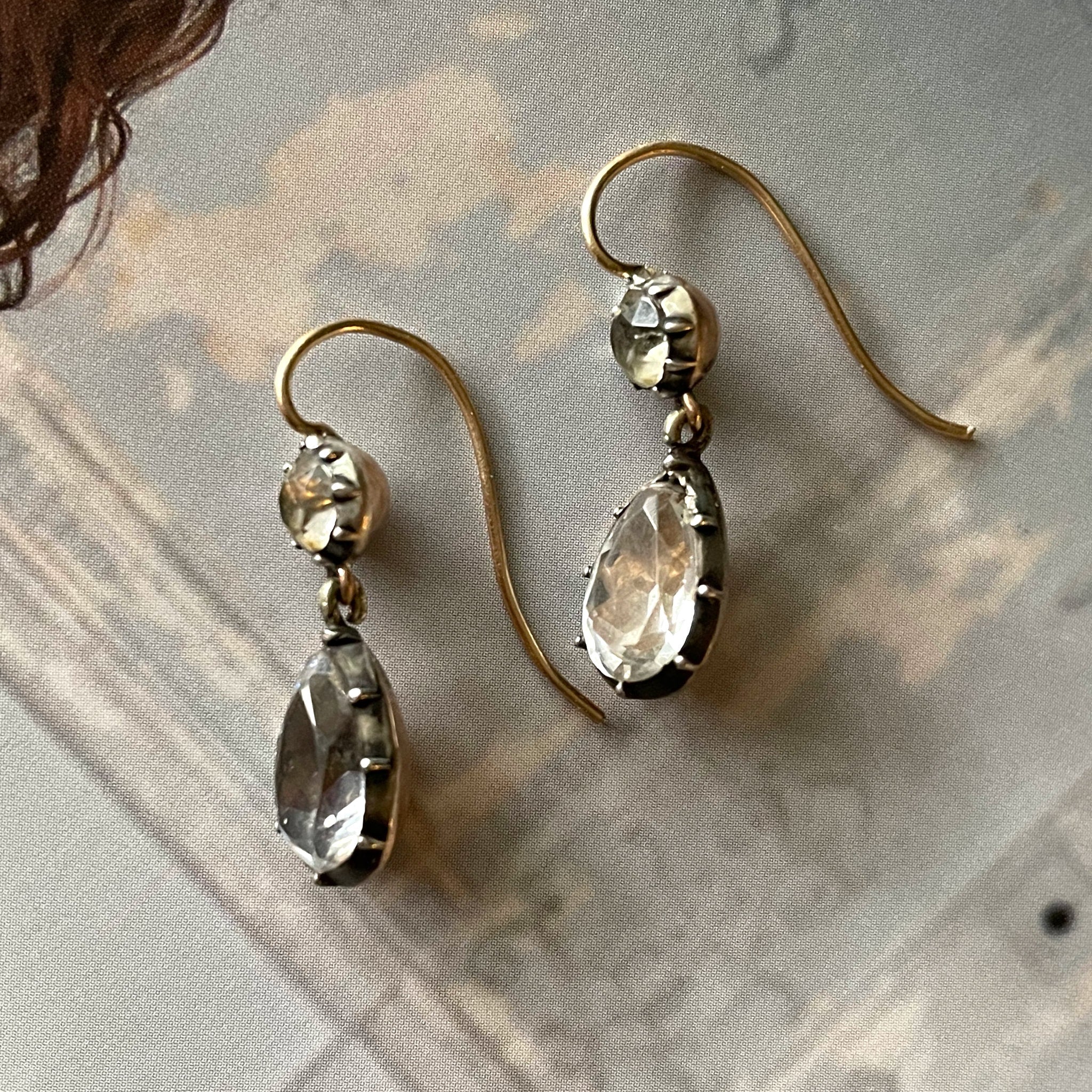 Antique white paste earrings on wallpaper background.