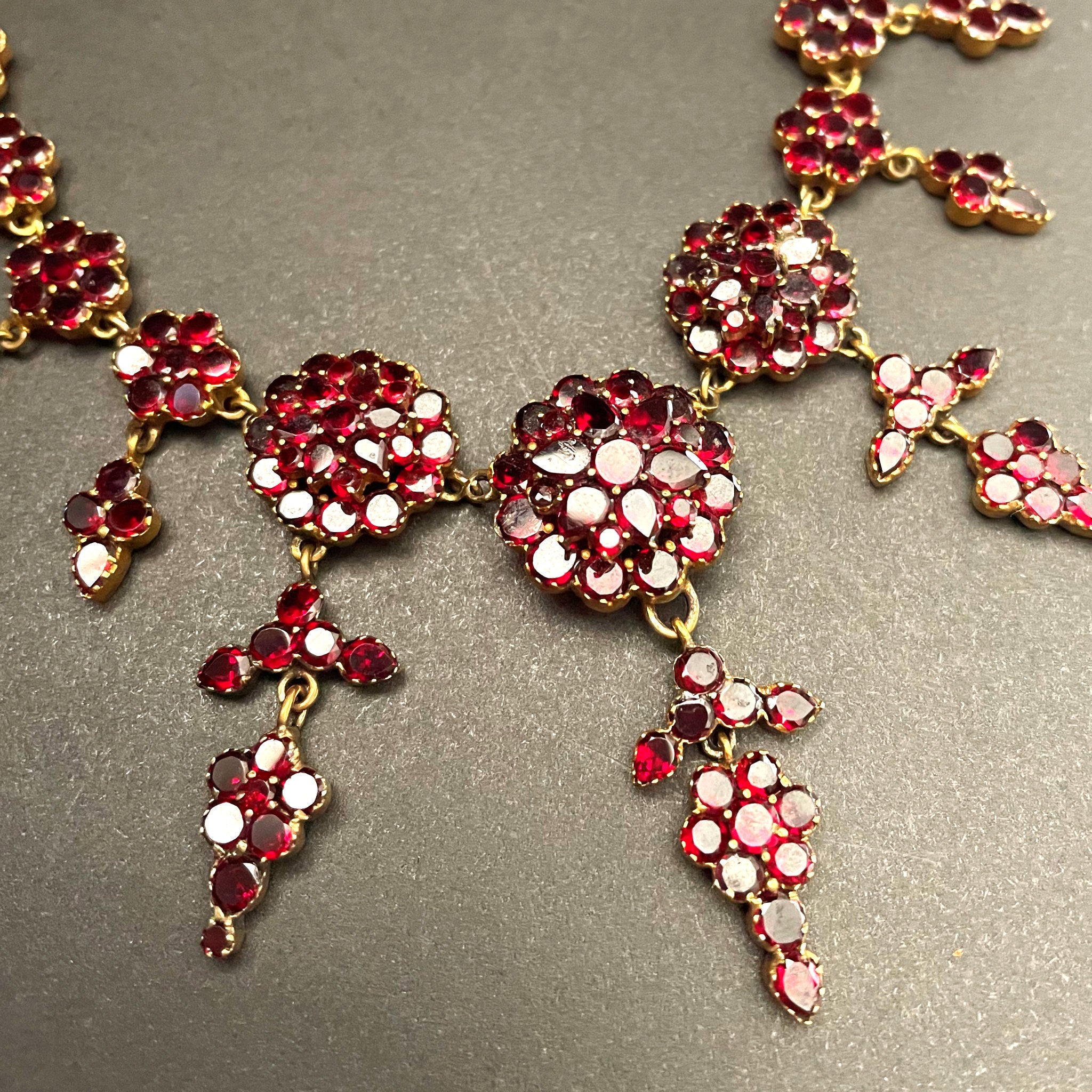 detail shot of intricate garnet drop necklace on black background