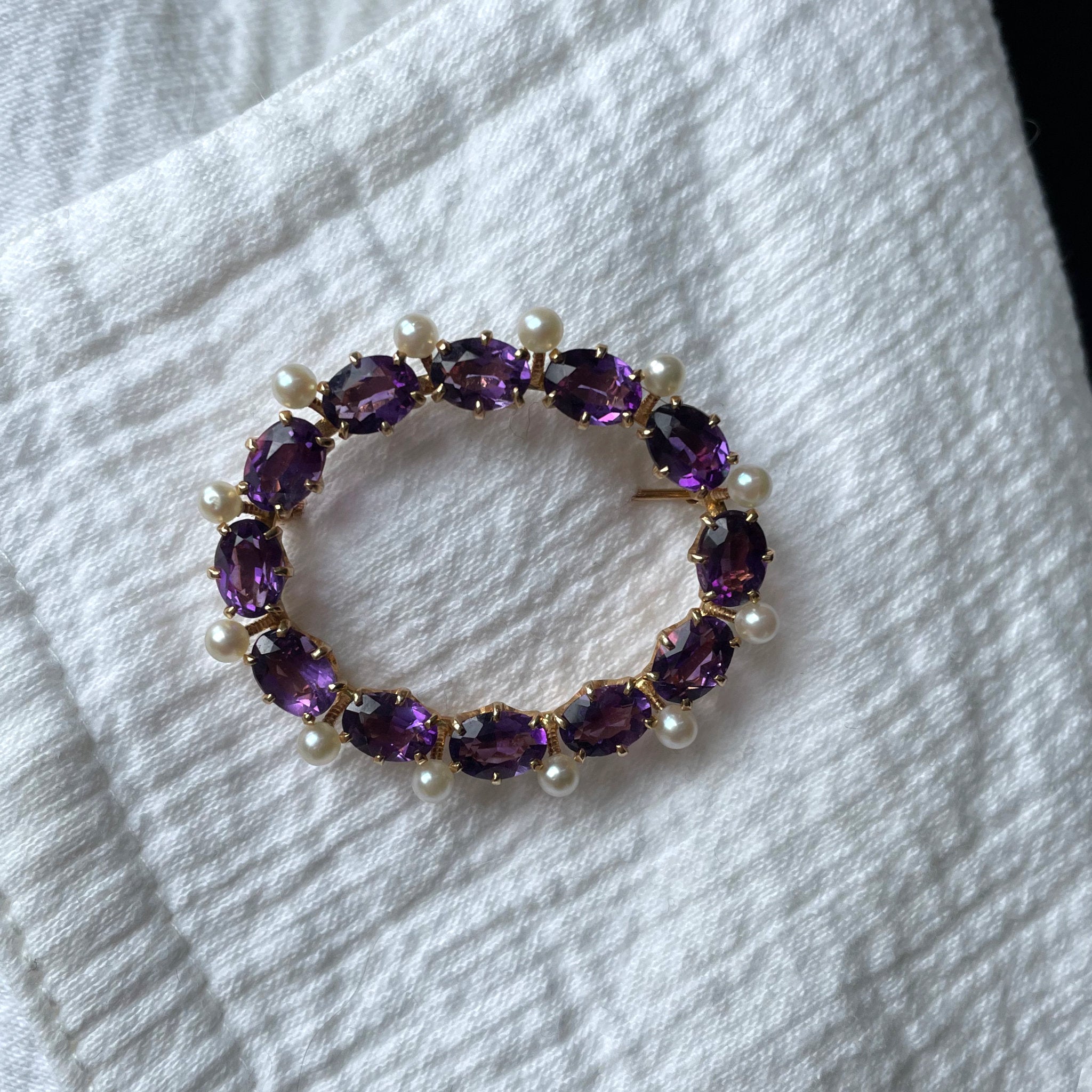 An oval brooch made of yellow gold, amethysts and pearls.