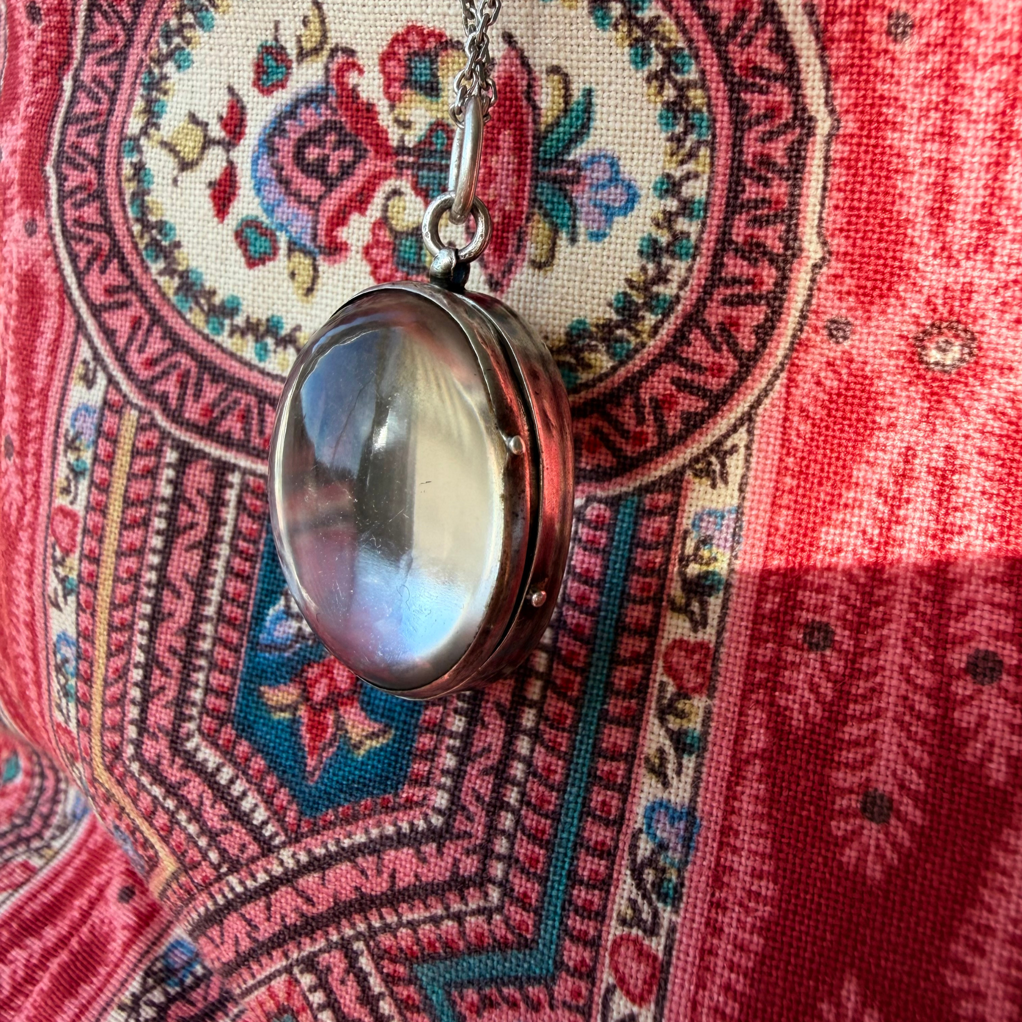 Necklace with a locket on a colorful patterned fabric background