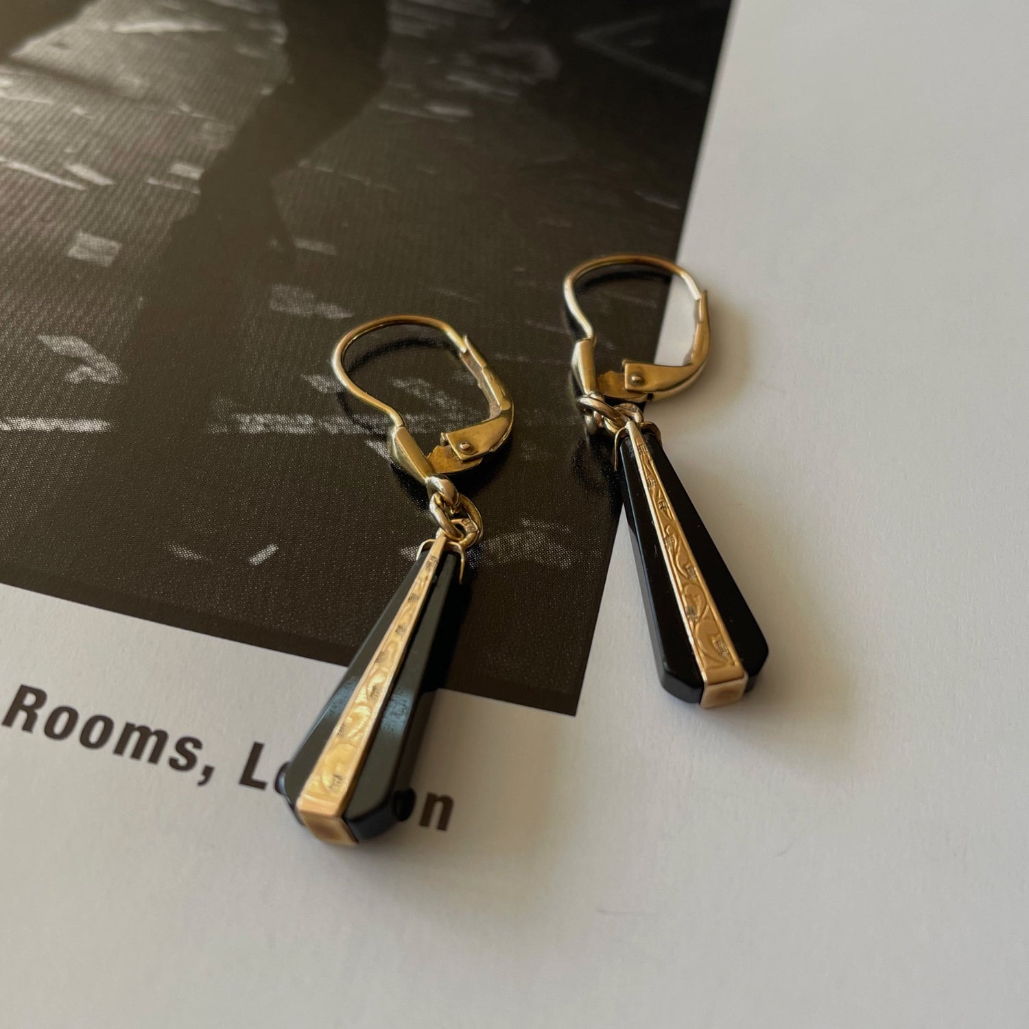 Art Deco earrings made of black onyx and gold on the page of a rock and roll photography book.