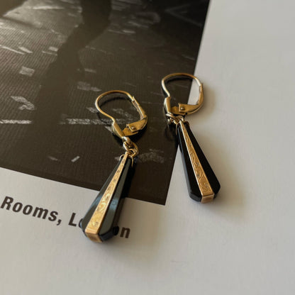 Art Deco earrings made of black onyx and gold on the page of a rock and roll photography book.