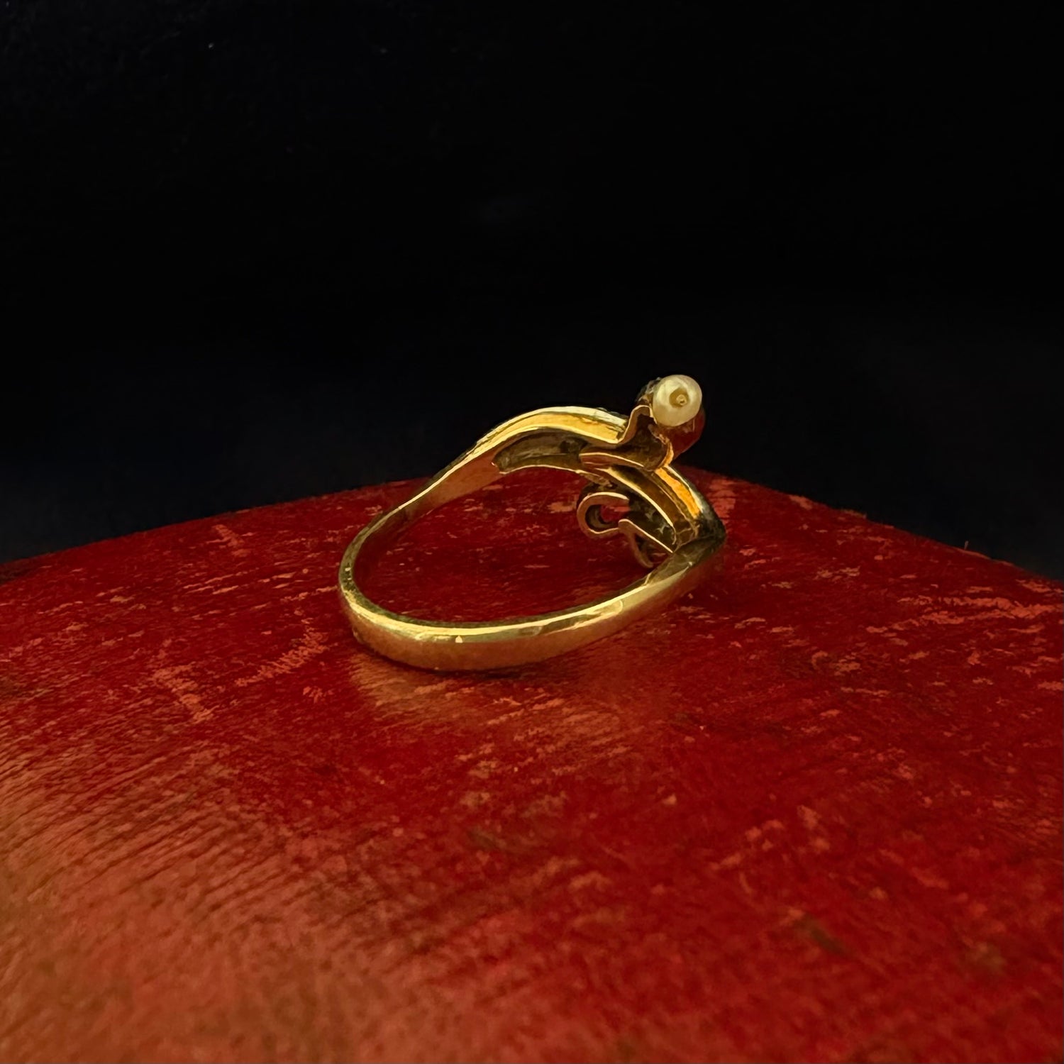 Gold ring with a pearl on a red surface