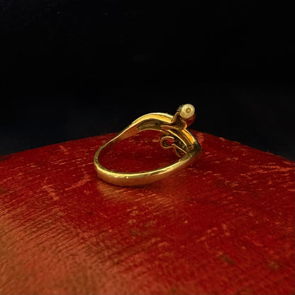 Gold ring with a pearl on a red surface