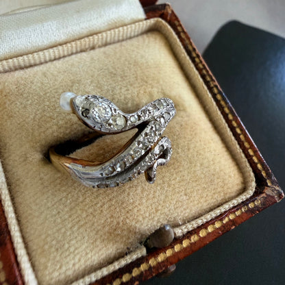 Silver and gold snake-shaped ring with a pearl in an open jewelry box