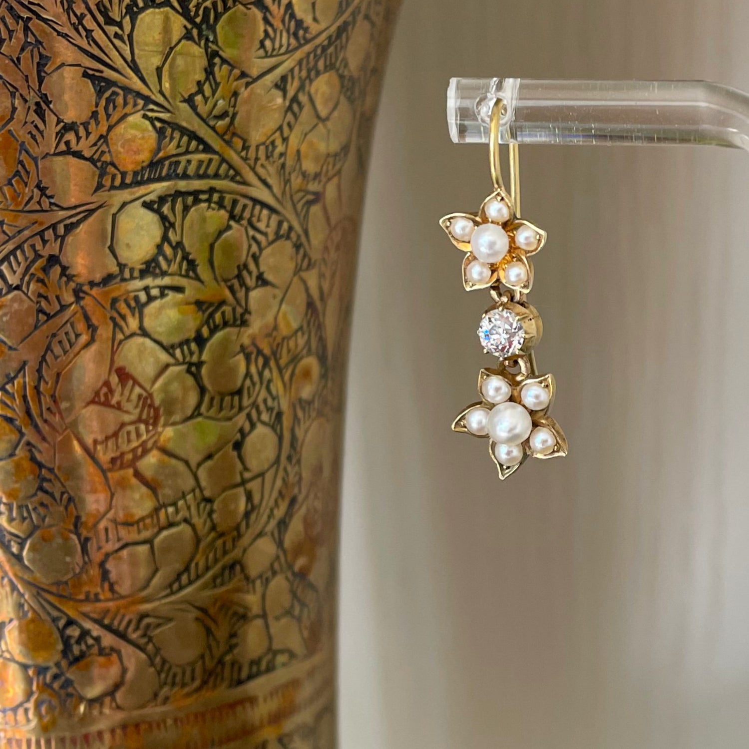 Detail of drop earrings made of yellow gold, pearl flowers and diamond drops.