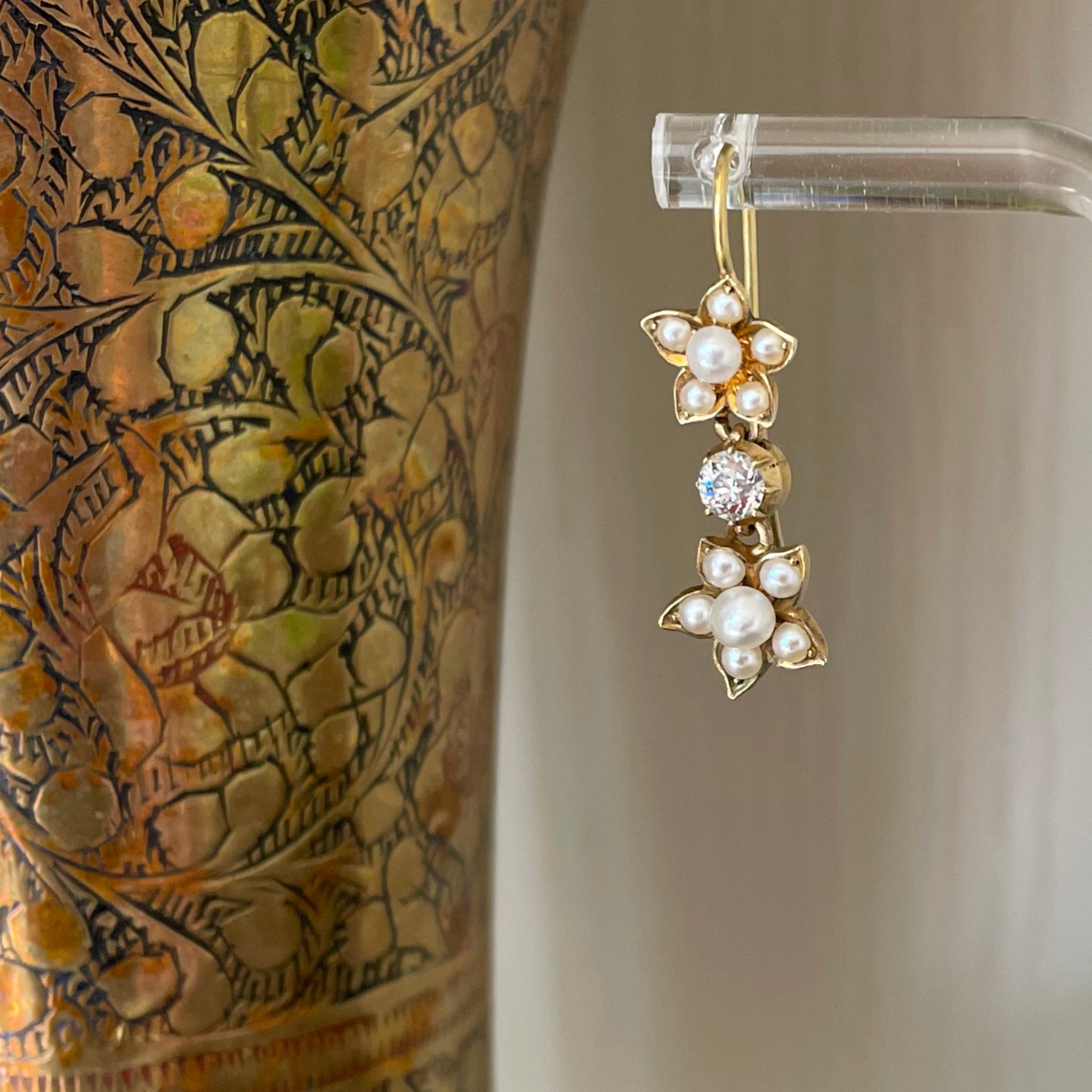 Detail of drop earrings made of yellow gold, pearl flowers and diamond drops.
