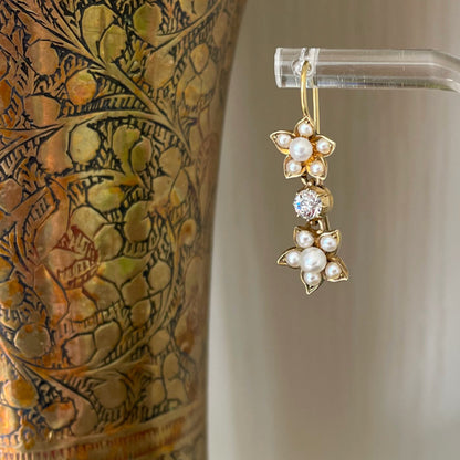 Detail of drop earrings made of yellow gold, pearl flowers and diamond drops.