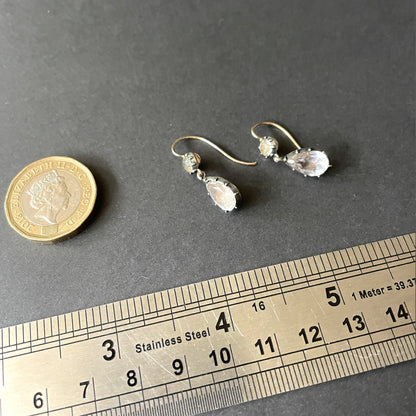 antique earrings next to ruler and pound coin.