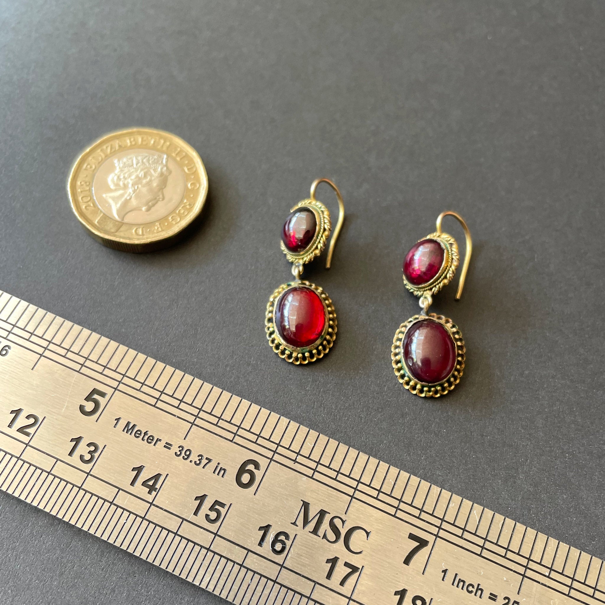 Garnet earrings on black background with gold chain.